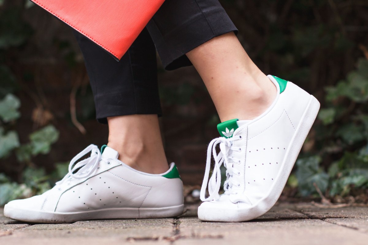 Kleidermädchen präsentiert einen Frühlingslook mit Herzbluse von Mango und Adidas Sneakers in Weiß, Grün und Schwarz.