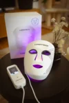 CurrentBody LED-Maske der 3. Generation mit Controller und Verpackung auf einem Beistelltisch.